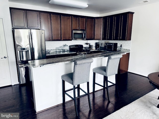 12 Canal Xing Unit 228, Burlington Township, NJ 08016 - kitchen featuring appliances with stainless steel finishes, decorative backsplash, stone counters, a breakfast bar area, and dark brown cabinets