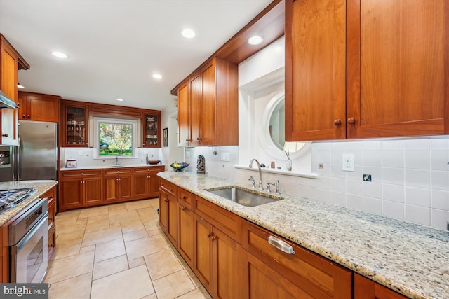 kitchen featuring brown cabinets, a sink, backsplash, and appliances with stainless steel finishes