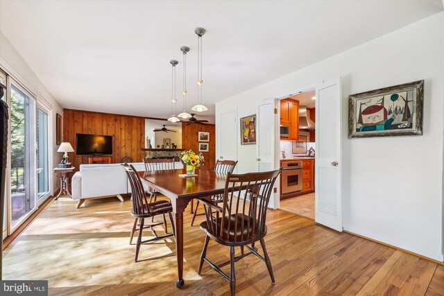 dining room with wooden walls, baseboards, and light wood-style floors