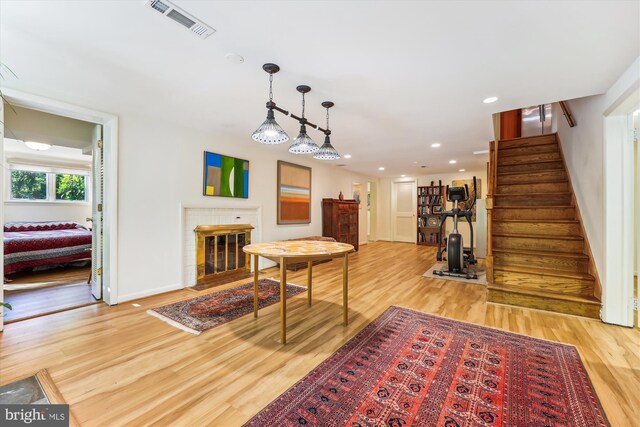 dining room featuring stairway, visible vents, light wood-style floors, baseboards, and a brick fireplace
