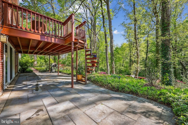 view of patio featuring a wooden deck, stairway, and a grill