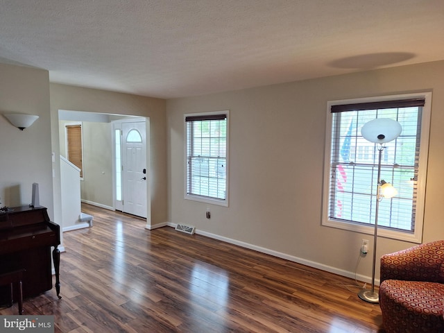entrance foyer featuring baseboards, visible vents, stairs, and dark wood-type flooring