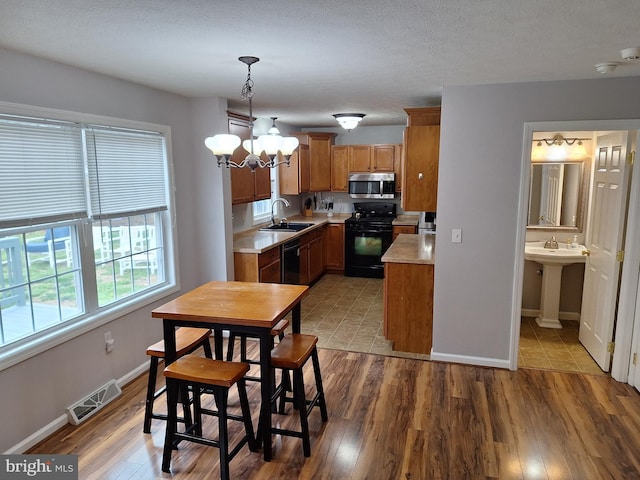 kitchen with brown cabinets, visible vents, black appliances, and light countertops