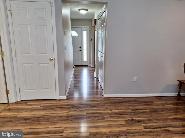 hall featuring baseboards and dark wood finished floors