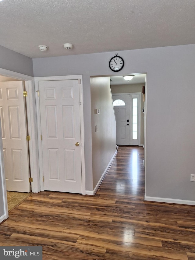 foyer featuring a textured ceiling, baseboards, and dark wood-style floors