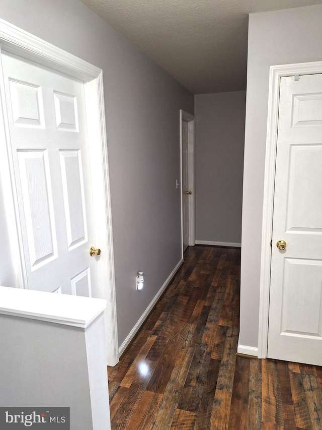 corridor with baseboards and dark wood-style floors