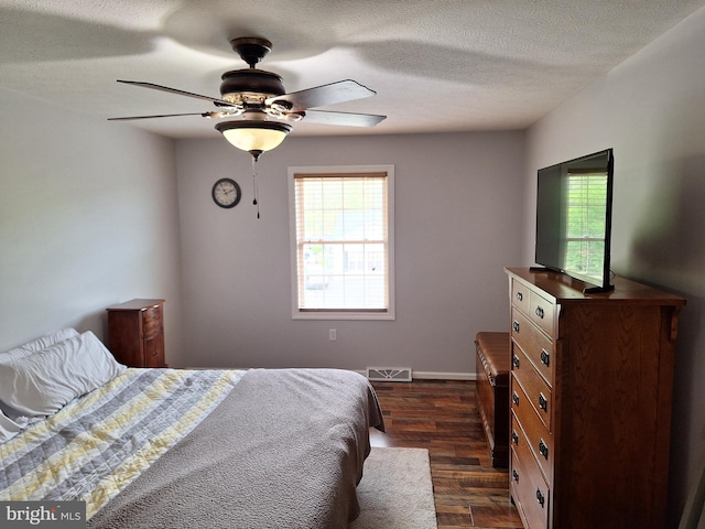 bedroom featuring dark wood-style flooring, a textured ceiling, visible vents, and multiple windows
