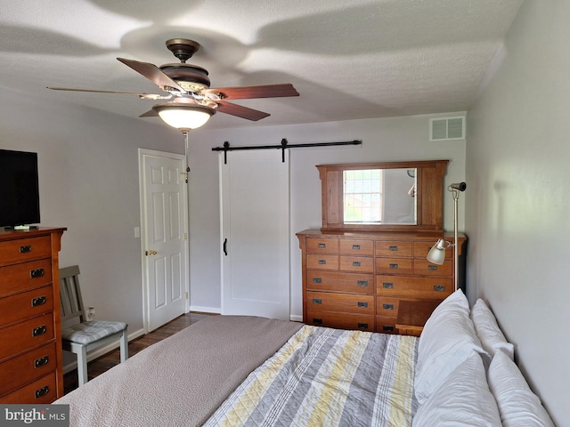 bedroom with a ceiling fan, a barn door, and visible vents