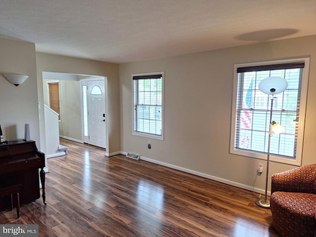 entryway with baseboards, visible vents, and dark wood-style floors