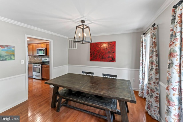 dining room with light wood-type flooring, visible vents, a notable chandelier, and crown molding