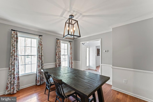 dining area featuring a chandelier, hardwood / wood-style floors, ornamental molding, and baseboards