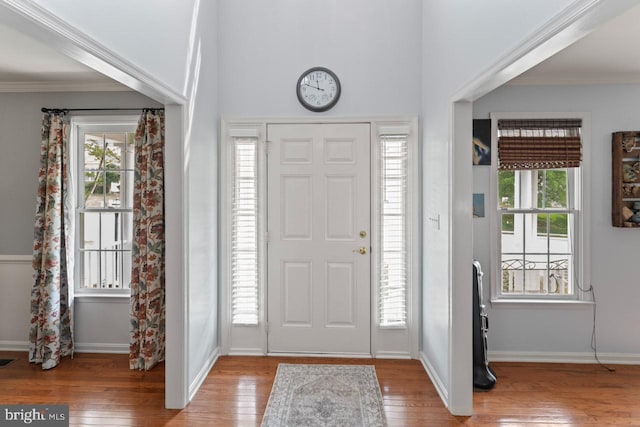 foyer entrance featuring ornamental molding, baseboards, wood finished floors, and plenty of natural light