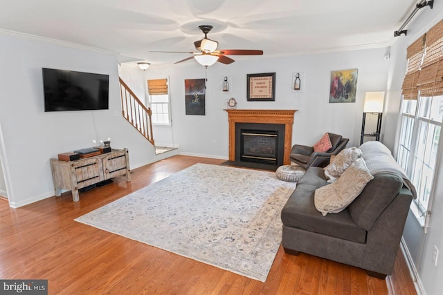living area featuring crown molding, baseboards, stairway, and plenty of natural light