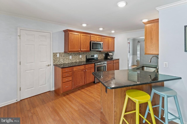 kitchen featuring stainless steel appliances, light wood finished floors, brown cabinetry, and a sink