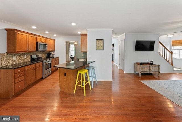 kitchen featuring a sink, stainless steel appliances, a breakfast bar area, a peninsula, and ornamental molding