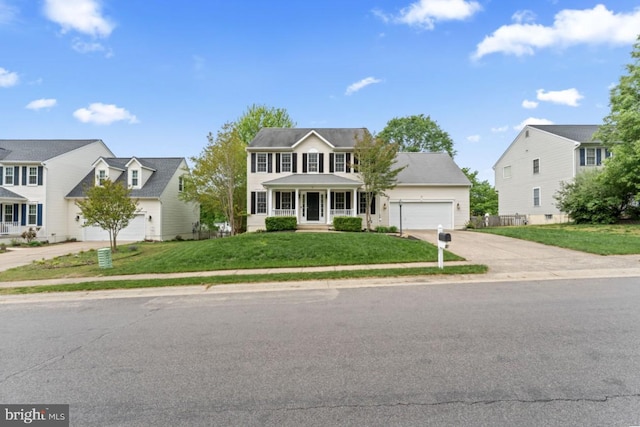 colonial-style house featuring a front yard, a garage, a residential view, covered porch, and driveway
