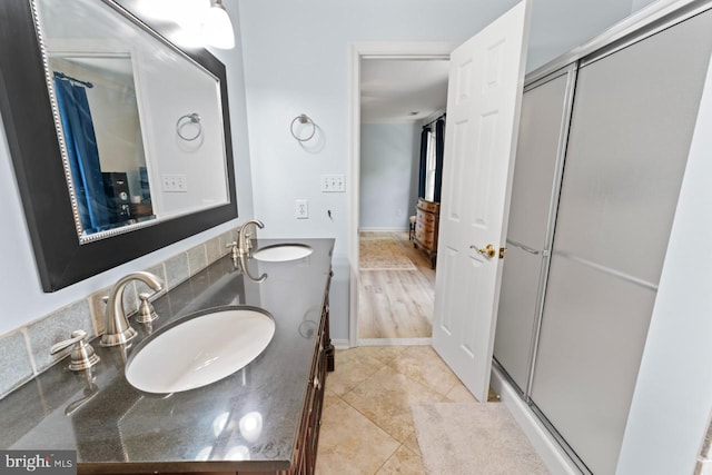 full bathroom with double vanity, a shower stall, tile patterned flooring, and a sink