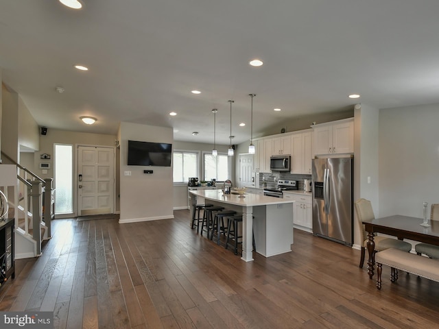 8362 Inspiration Ave, Walkersville, MD 21793 - kitchen with baseboards, a kitchen island with sink, appliances with stainless steel finishes, a breakfast bar area, and white cabinetry