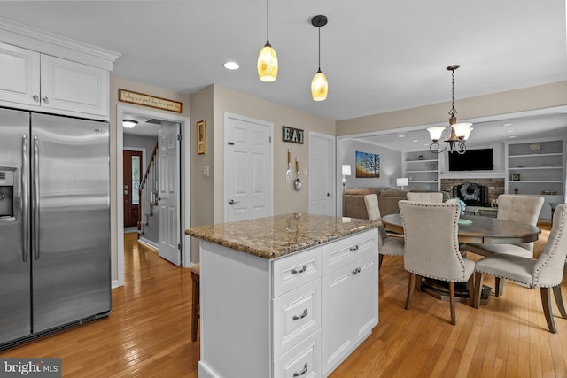 kitchen with light wood finished floors, stainless steel fridge with ice dispenser, white cabinets, decorative light fixtures, and a chandelier