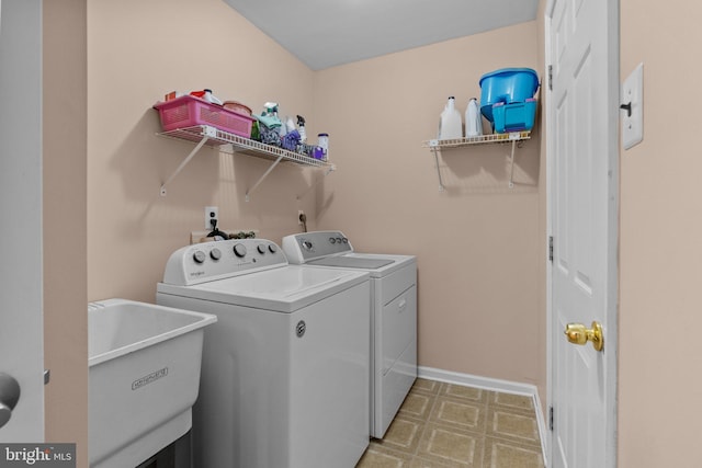 washroom with washing machine and dryer, a sink, laundry area, light floors, and baseboards