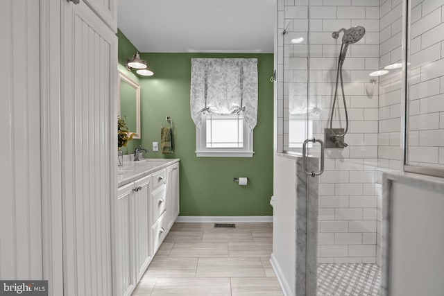 full bath featuring a stall shower, vanity, baseboards, and visible vents