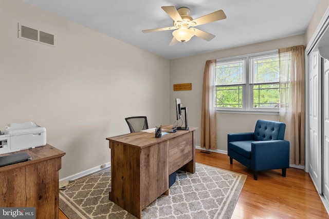 office area with light wood-style flooring, baseboards, a ceiling fan, and visible vents