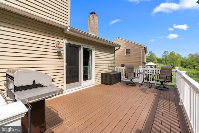 wooden terrace with outdoor dining area and a grill