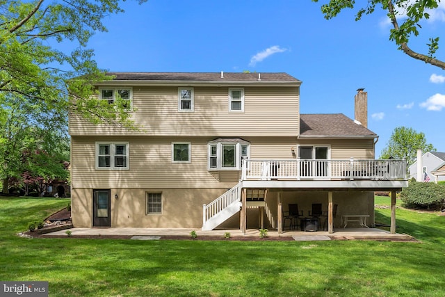 rear view of house with a patio area, a chimney, a deck, and a lawn