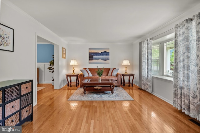living area with baseboards, ornamental molding, visible vents, and hardwood / wood-style flooring