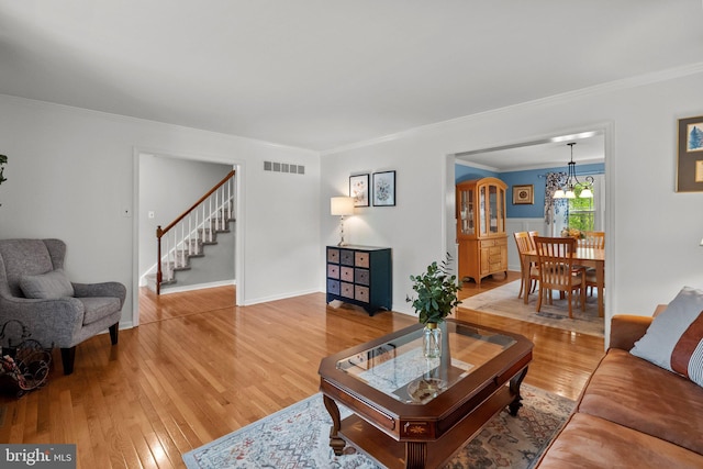 living room with ornamental molding, light wood finished floors, and visible vents