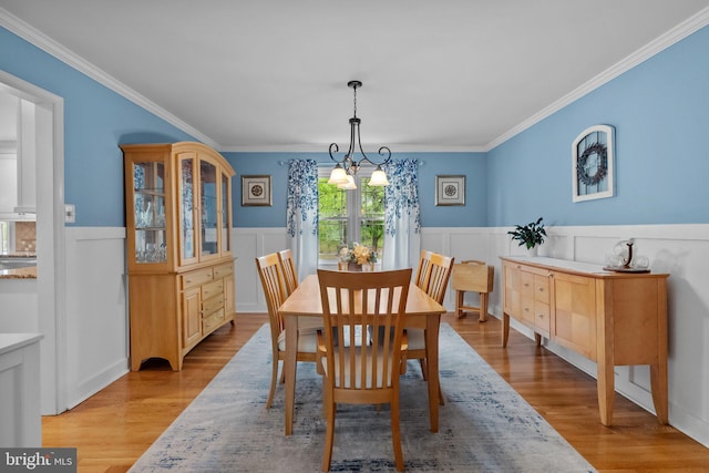 dining room with crown molding, light wood-style floors, and wainscoting