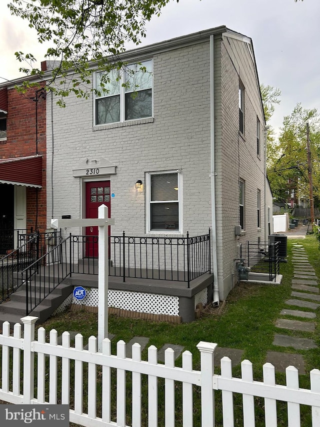 townhome / multi-family property with brick siding, central AC, and a fenced front yard