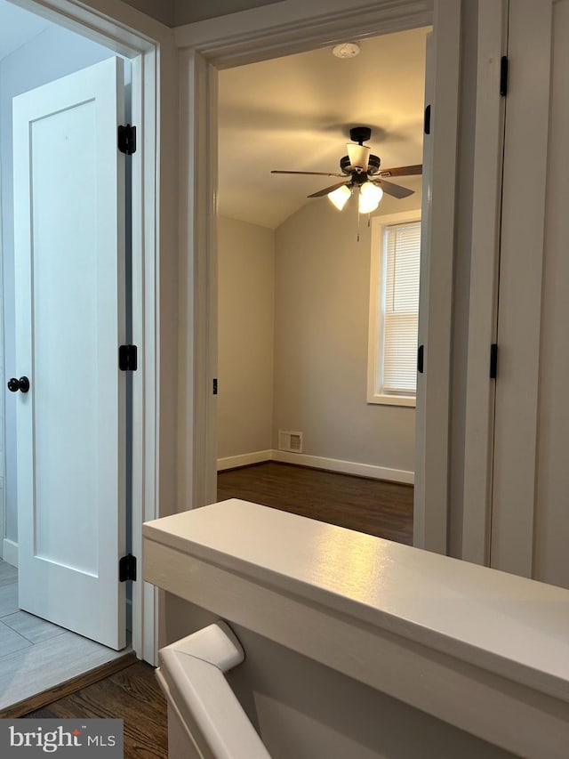 corridor with dark wood-type flooring, baseboards, and visible vents