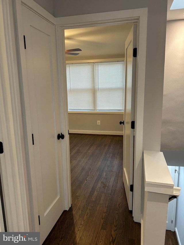 corridor with baseboards and dark wood-style flooring