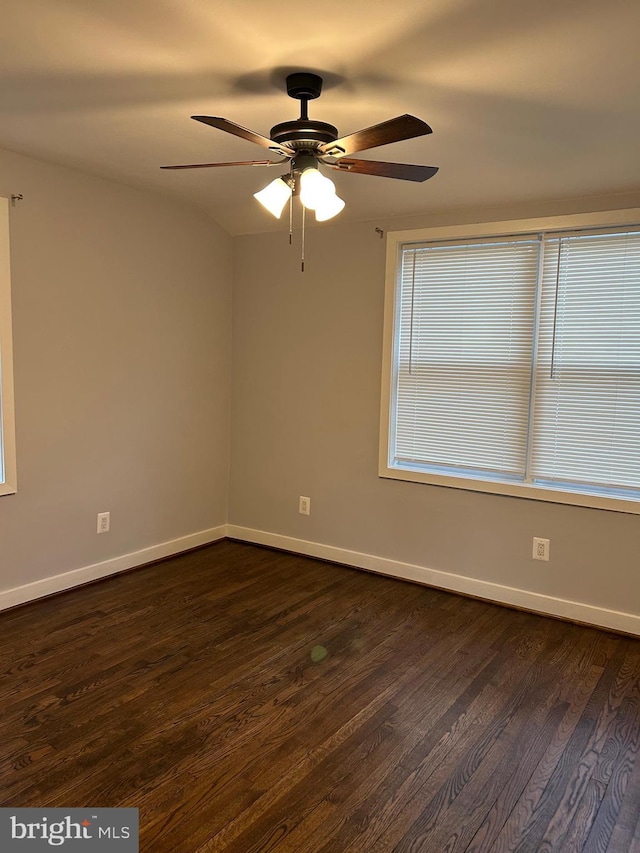 empty room featuring dark wood-style flooring, baseboards, and ceiling fan