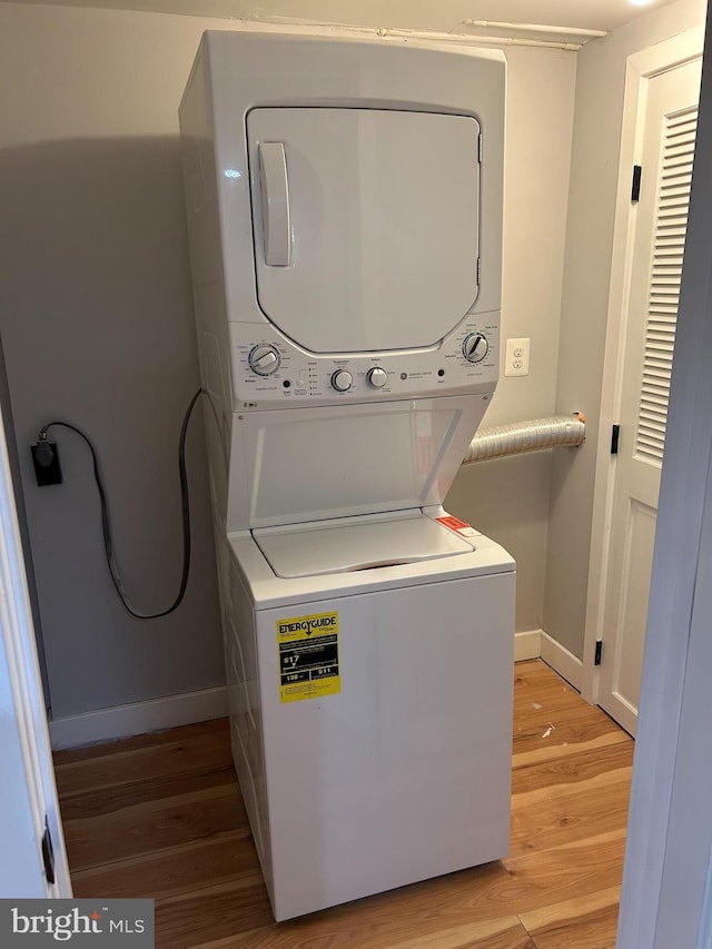 washroom featuring baseboards, laundry area, light wood-style floors, and stacked washing maching and dryer