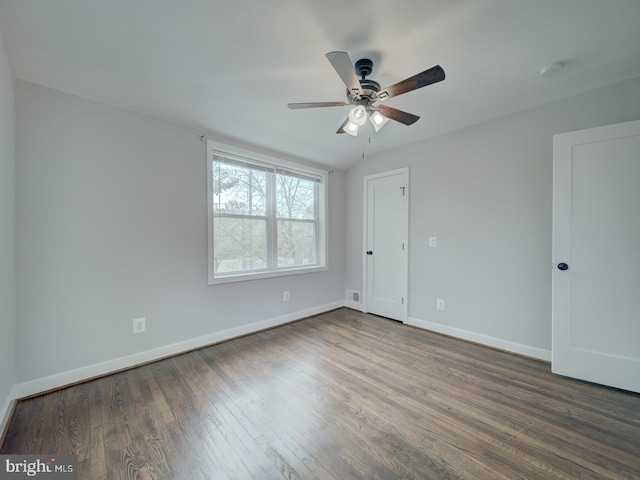 empty room with baseboards, a ceiling fan, and dark wood-style floors