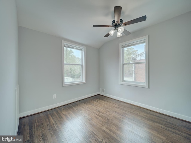 empty room with dark wood-type flooring, baseboards, a healthy amount of sunlight, and vaulted ceiling