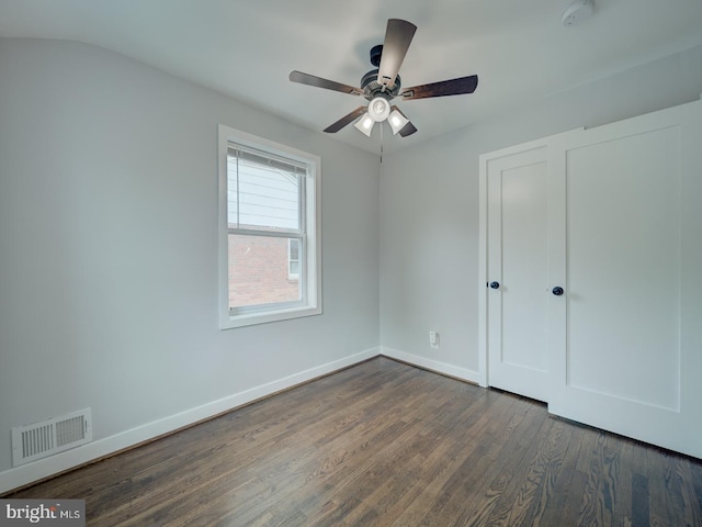 unfurnished bedroom with baseboards, ceiling fan, dark wood-style flooring, and visible vents