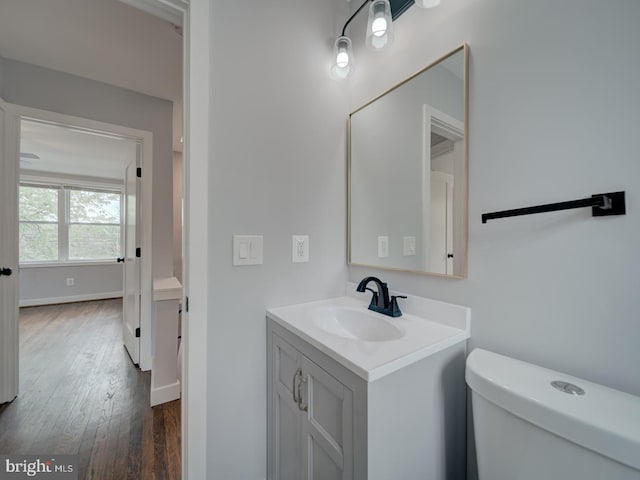bathroom with toilet, baseboards, wood finished floors, and vanity