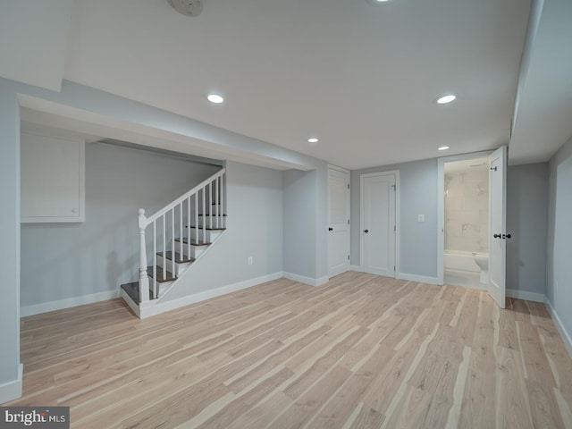 finished basement featuring recessed lighting, baseboards, light wood-type flooring, and stairs