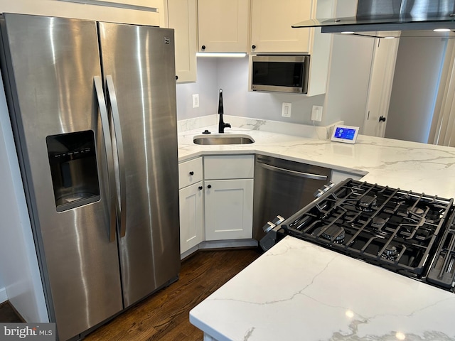 kitchen featuring light stone countertops, dark wood finished floors, a sink, stainless steel appliances, and white cabinetry
