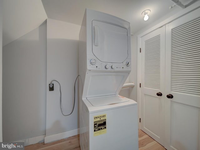 laundry area with baseboards, laundry area, light wood-style flooring, and stacked washer and clothes dryer