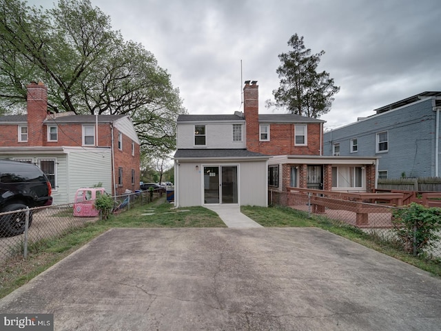 rear view of property featuring fence, a chimney, and brick siding