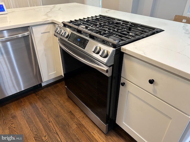 kitchen featuring dark wood-style flooring, light stone counters, stainless steel appliances, white cabinetry, and visible vents