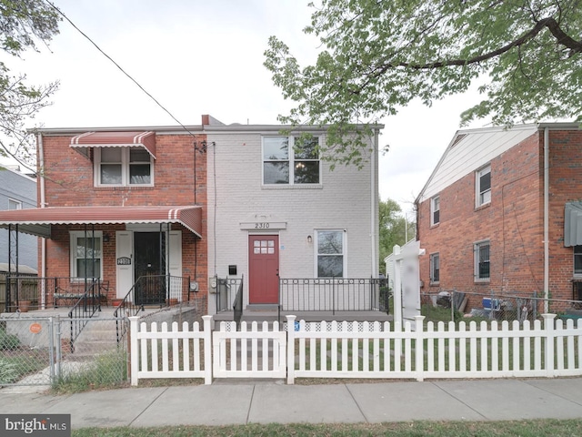 view of front of house featuring covered porch, brick siding, and a fenced front yard