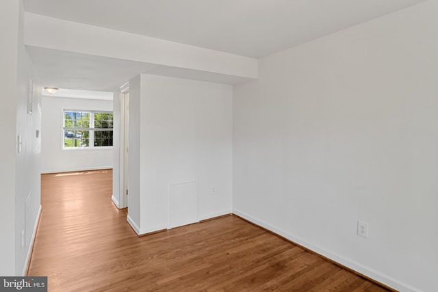 spare room featuring baseboards and wood finished floors