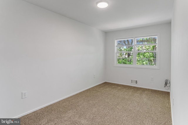 carpeted spare room with visible vents and baseboards