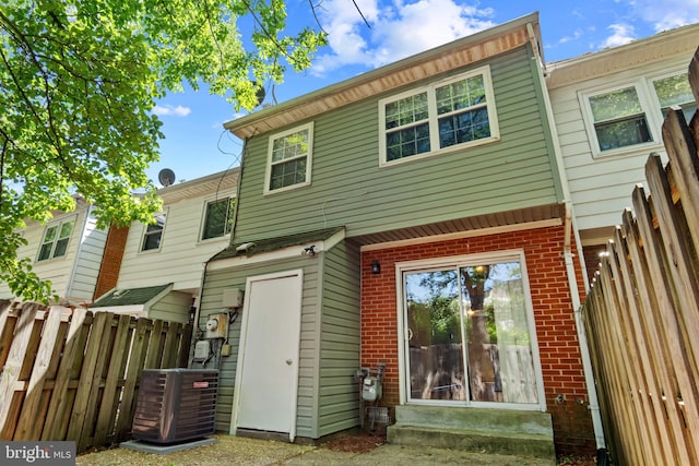 back of house with brick siding, entry steps, fence, and cooling unit
