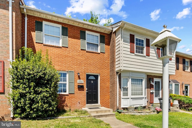 view of property featuring brick siding, entry steps, and a front lawn